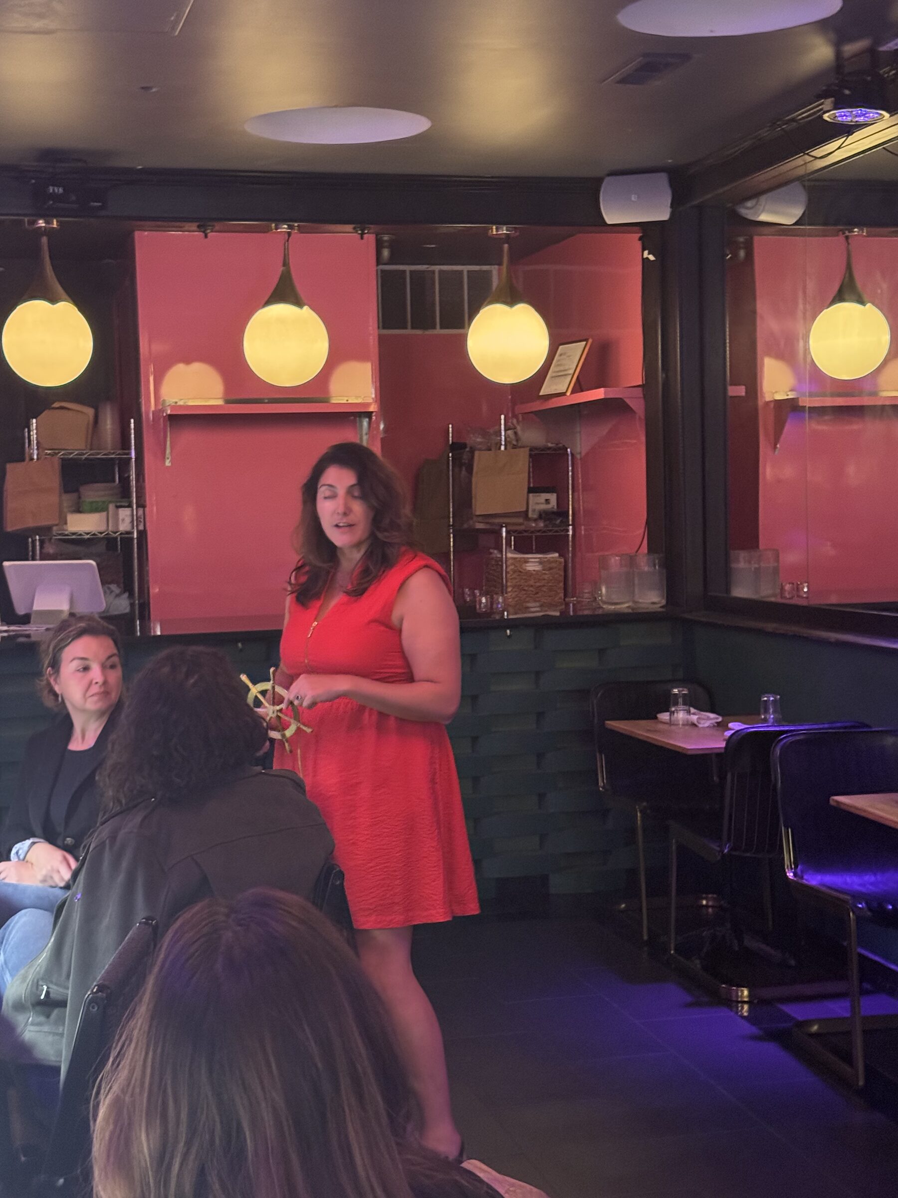 Host in a coral dress speaking to guests beside the pink bar alcove in Philadelphia