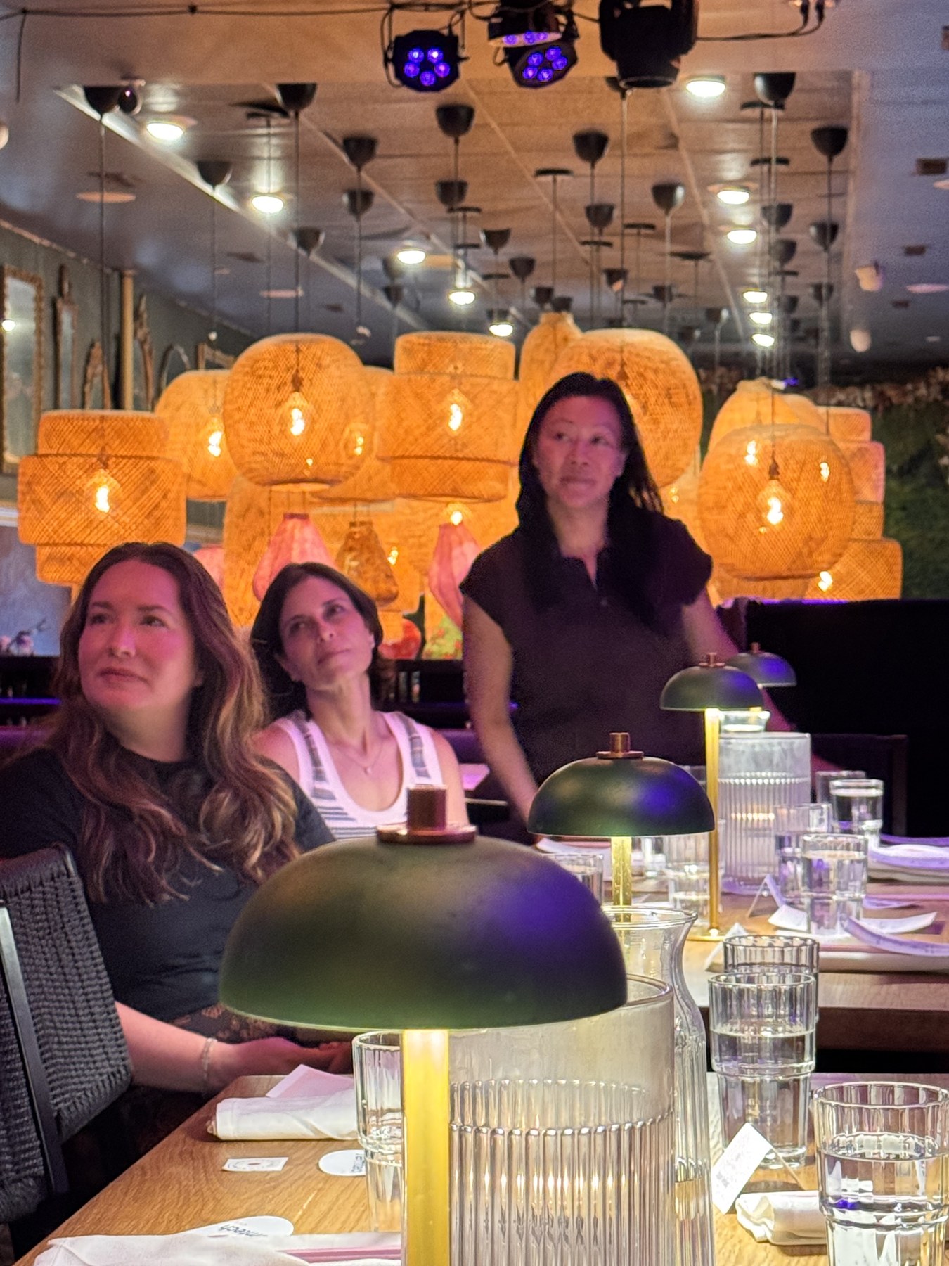 Guests seated at the Philadelphia table under rattan pendant lights