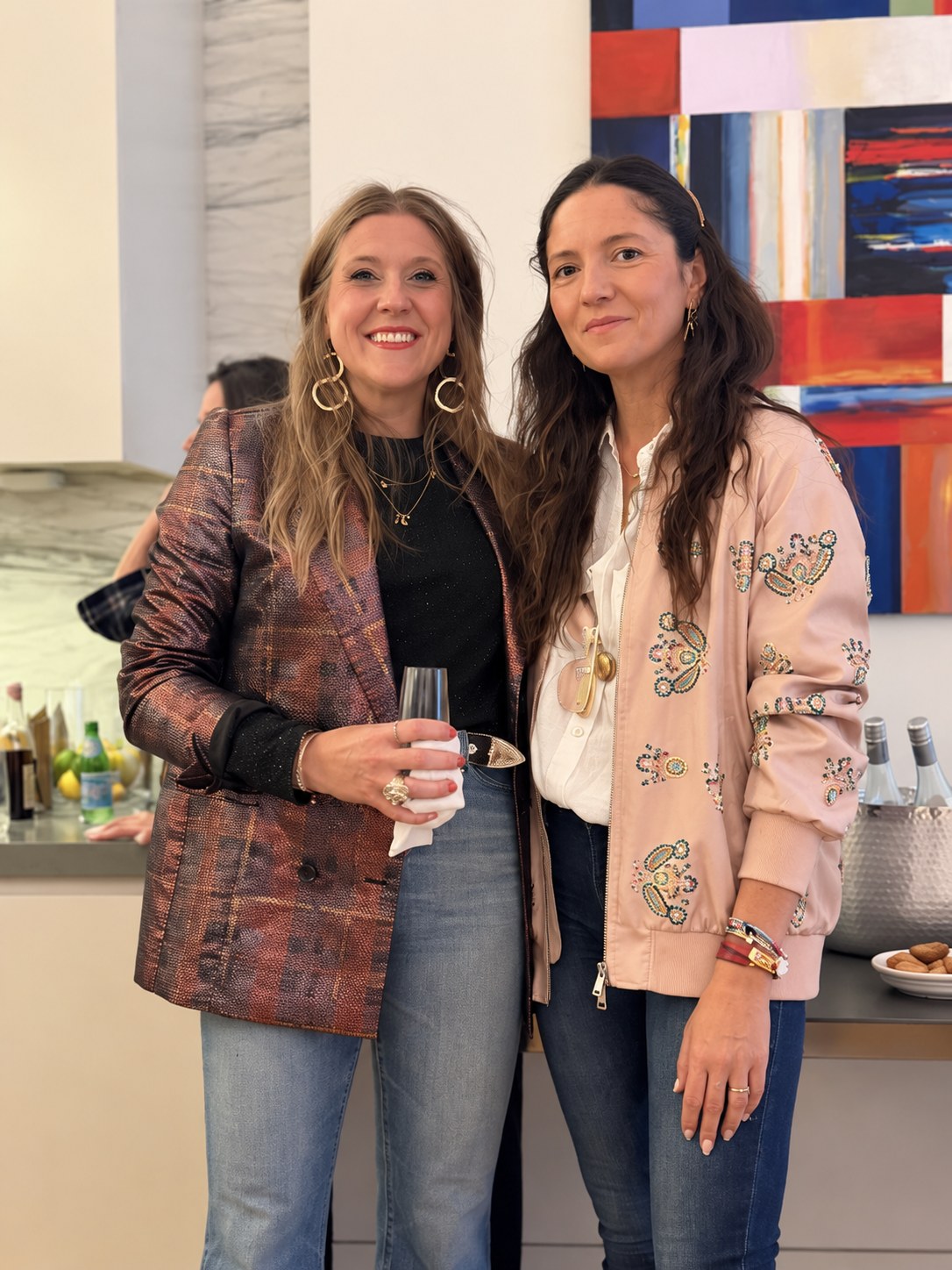 Two guests posing in front of the colorful abstract painting at Rosé at the Helm